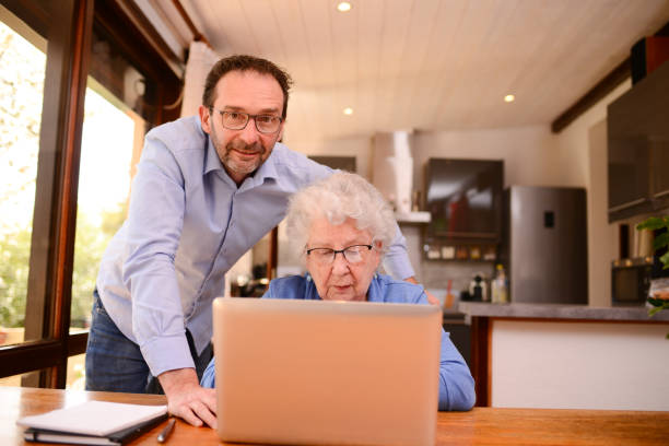 istock mature man helping elderly senior woman at home with paperwork and computer internet lesson 1318738169