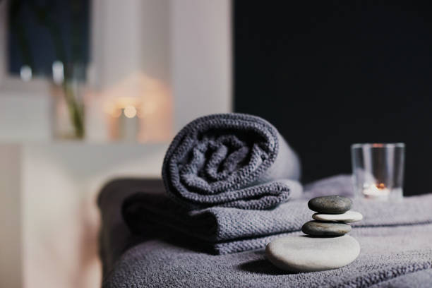 Beautiful young woman relaxes on a spa bed surrounded by nature. ready for a body massage. Attractive female in white towel lying peacefully during waiting for body massage. Close up. Tranquility