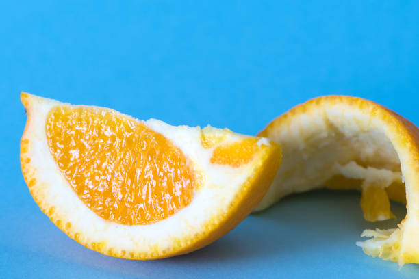 istock Orange peel and orange wedge on blue background 1318752158