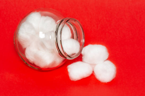 Cotton Wool Balls Cotton balls jar isolated on a red background. Fluffy clean white cotton balls stored in a glass bottle. cotton cotton ball fiber white stock pictures, royalty-free photos & images