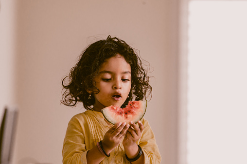 little girl eating watermelon at home, India