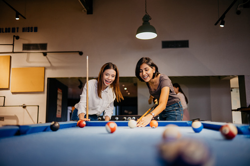 Young woman office workers playing pool in the office