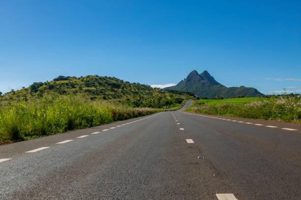 istock Road with mountains blue sky in the background 1318776656