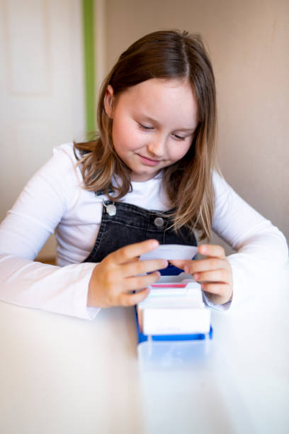 pretty young schoolgirl sitting on her desk in her room at home learning english vocabulary using flashcards - pre teen boy flash imagens e fotografias de stock