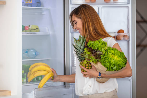 istock Happy young woman standing at the opened fridge. 1318778413