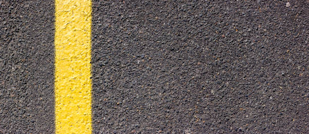 istock Asphalt texture with a yellow line on the left side. Road surface with markings. 1318780473
