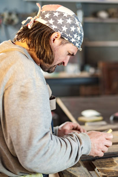 istock Male carpenter working on old wood in a retro vintage workshop. 1318786392