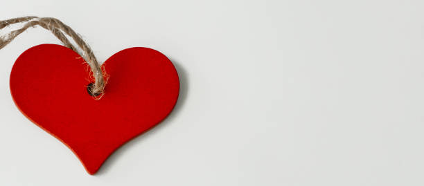 istock wooden red heart on a string, on a white background, banner 1318786472