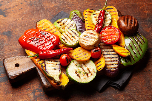 Grilled vegetables with spices and herbs on cutting board