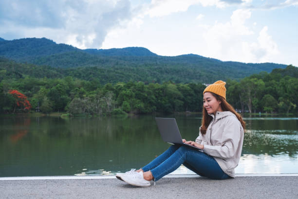 istock A young asian woman using and working on laptop computer while traveling mountains and lake 1318789463
