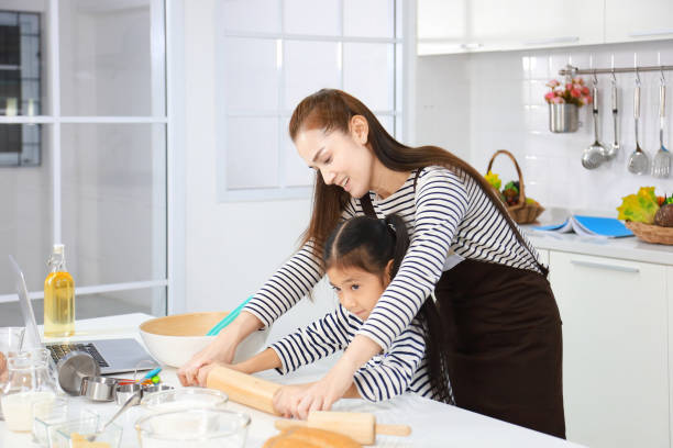 happy asian mother teaching her daughter to bread baking in white modern kitchen while kneading flour to make dough - bun bread 7 grain bread dough imagens e fotografias de stock