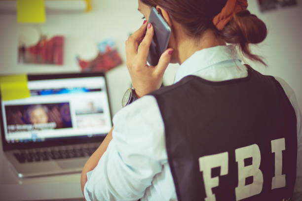 FBI woman in office talking on phone. FBI woman in office talking on phone.  Focus is on foreground. fbi photos stock pictures, royalty-free photos & images