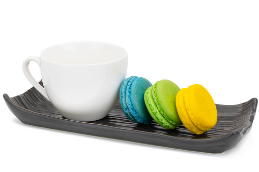 A row of colorful macaroons on a ceramic tray, isolate don white background.