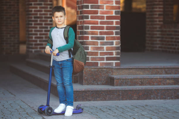 istock School boy in casual clothes and backpack goes to school on a scooter 1318798092