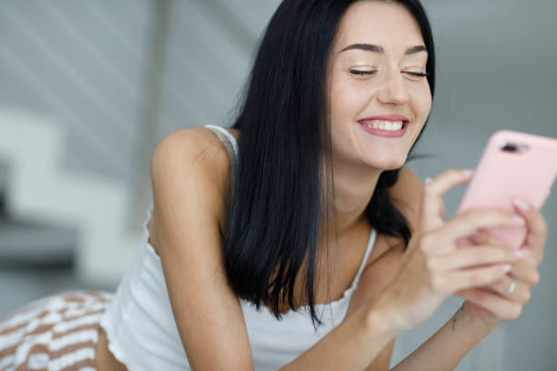 istock Happy young woman with a joyful grin using her mobile phone 1318798217