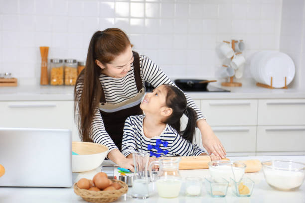 mãe asiática feliz ensinando sua filha a assar pão na cozinha branca moderna enquanto amassa farinha para fazer massa - bread food baked 7 grain bread - fotografias e filmes do acervo