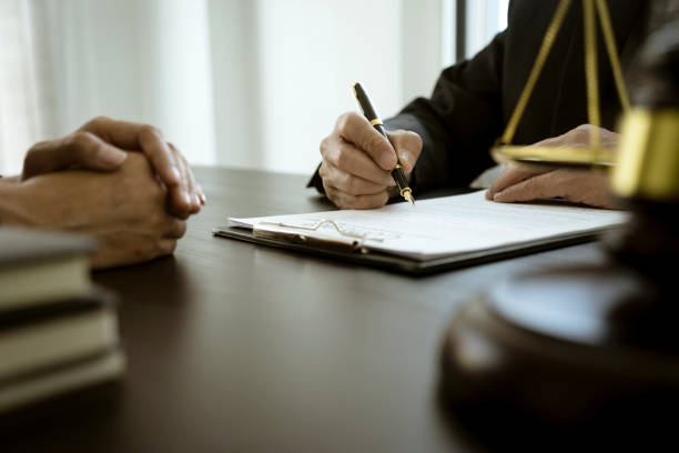 el abogado está escribiendo redactando un documento legal mientras escucha la información del cliente - drafting fotografías e imágenes de stock