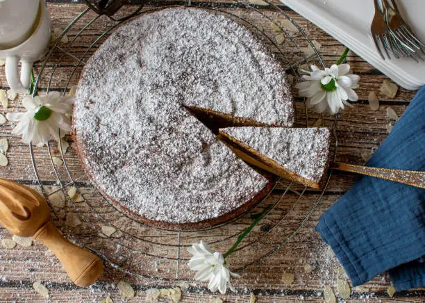 gluten free almond cake from spain, tarta de santiago served on rustic wooden table background isolated from above