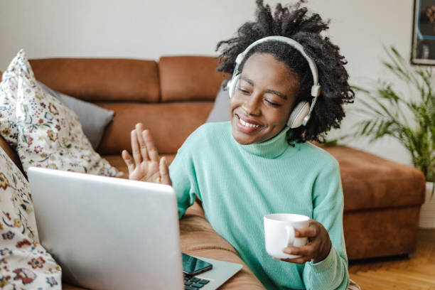 istock Young African American woman is working from home on laptop while drinking coffee 1318805412