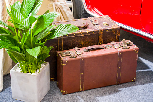 Leather travel suitcase placed on the antique old wooden wardrobe.