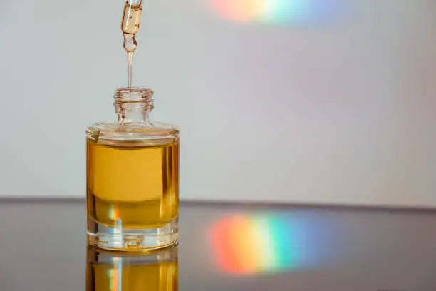 Face oil on reflective surface with a rainbow streak. Flowing serum