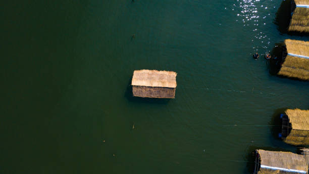 太陽の光が水に反射する湖の風景の竹いかだコテージ - looking at view on top of nautical vessel high section ストックフォトと画像