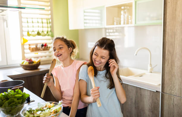 istock Two girls singing in the kitchen holding spoon 1318810455