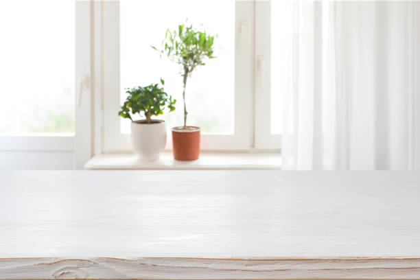 istock Wood texture table on blurred window sill with houseplants background 1318810806