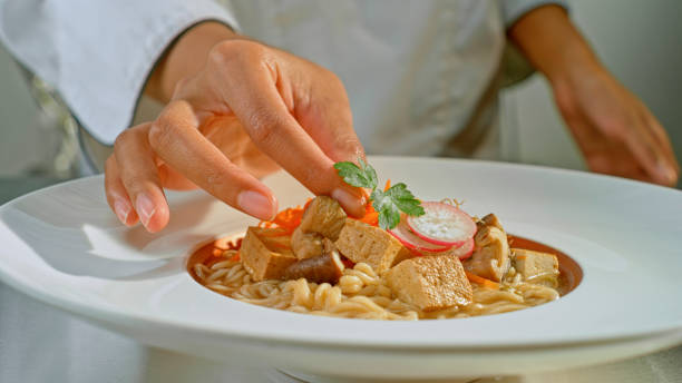 istock Woman adding coriander herb to the vegetarian ramen soup 1318814400