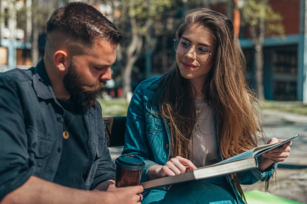 istock Two students sitting on a bench in a campus and studying for their exam 1318822275