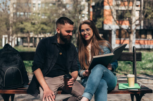 istock Two students sitting on a bench in a campus and studying for their exam 1318822290