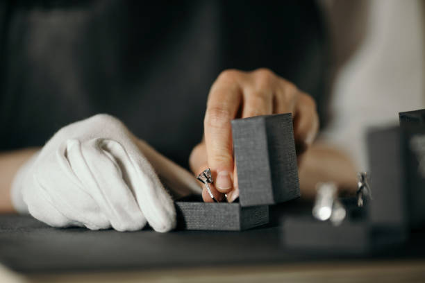 Jewelry manufacture Close up shot of jeweler hand while packing ring made of precious metal and gem in box for selling in jewelry manufacture workshop jewelry store stock pictures, royalty-free photos & images