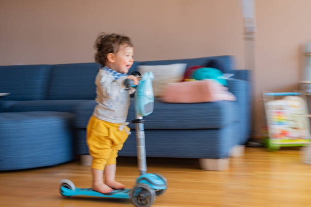 istock Boy riding scooter indoors 1318828031