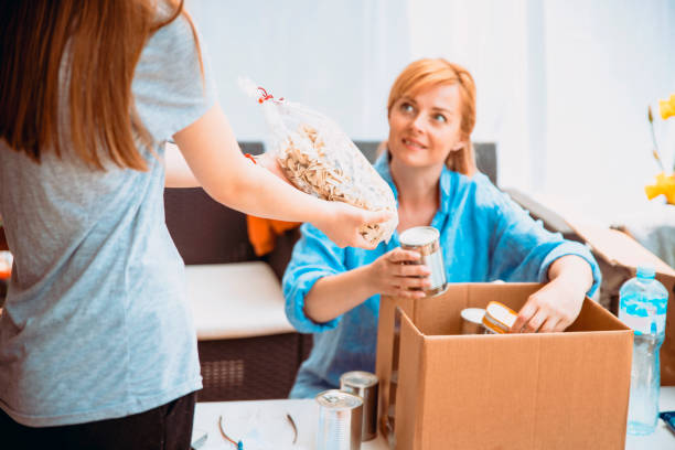 mujeres que recogen un paquete para la donación - supermarket women packaging blond hair fotografías e imágenes de stock