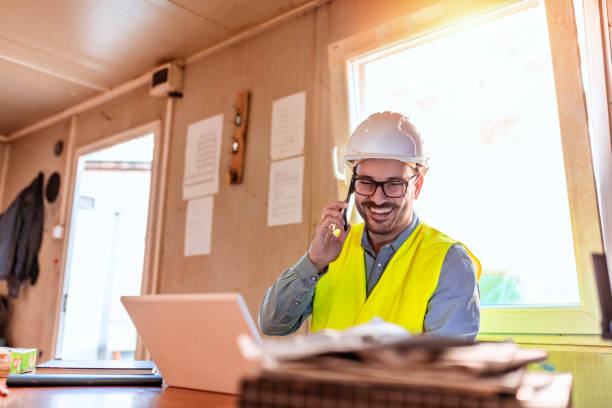 istock Architect working while talking on smartphone in front of white laptop. 1318828552