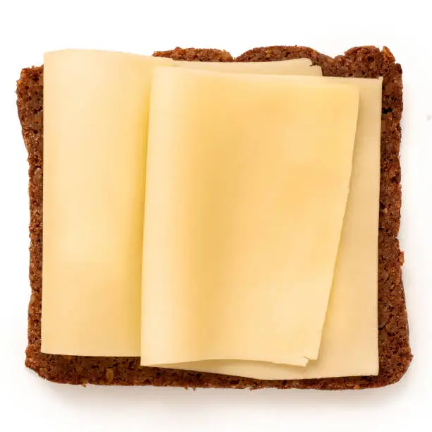 Two folded thin slices of yellow cheese on German health bread isolated on white. Top view.