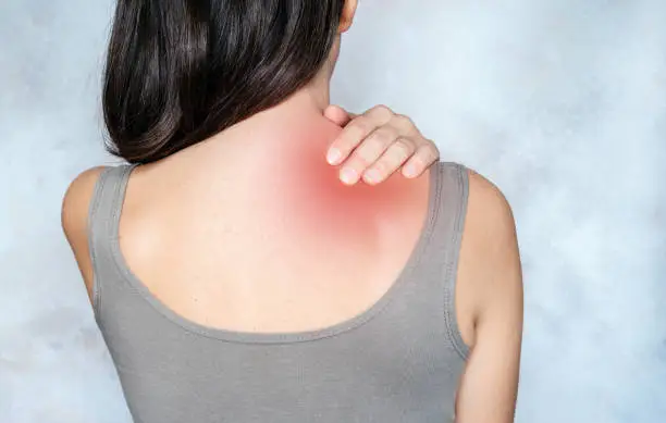 A woman massages her shoulder and neck pain points, trigger point massage, physiotherapy, and massage concept