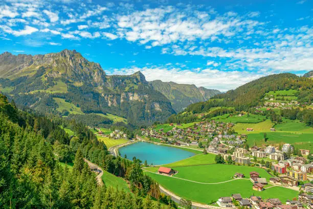 Valley of Engelberg with Eugenisee lake. View from cable car to Titlis mountain of the Uri Alps. Located in cantons of Obwalden and Bern, Switzerland, Europe. Summer season, clear blue sky.