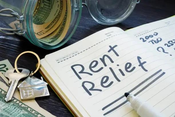 Photo of Rent relief sign and almost empty jar with money.