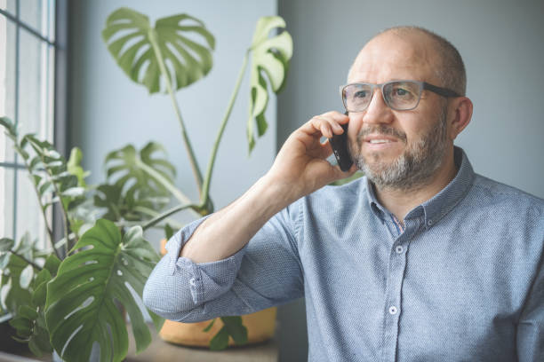 istock mature adult man working from home office (smart phone-2) 1318842351