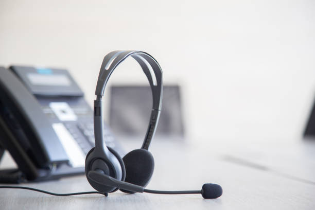 istock Communication support, call center and customer service help desk. VOIP headset on telephone keyboard. 1318845388