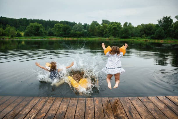 istock Children having fun on a lake jumping into water 1318847541