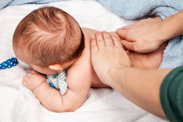 Little baby receiving chiropractic treatment of her back at home stock photo