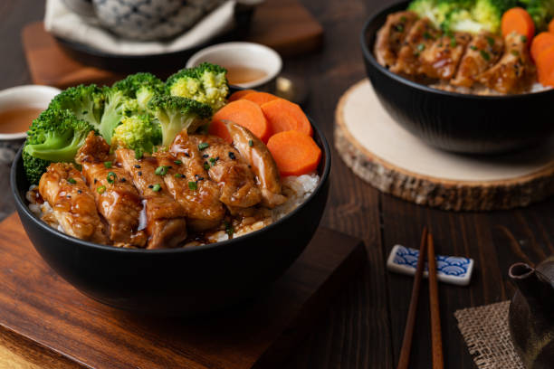 japanese food style : homemade chicken teriyaki grilled with rice , carrot , broccoli put on the black bowl and place on wooden table - teriyaki broccoli carrot chicken imagens e fotografias de stock
