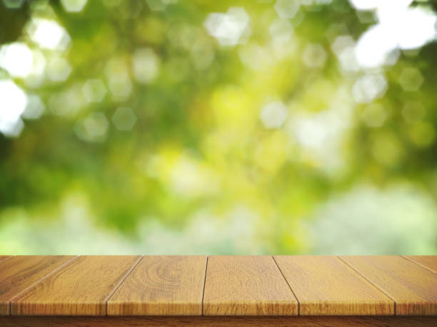 istock Empty wooden table top with foliage bokeh background suitable for montage product display 3d rendering 1318854595