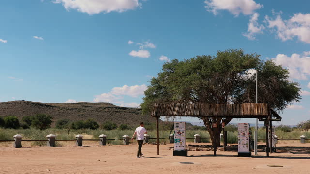 Man traveler walking to the abandoned fuel station in Namibia during sunny day