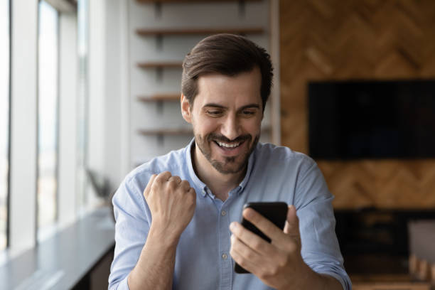 istock Excited man celebrate promotions message on cellphone 1318858230