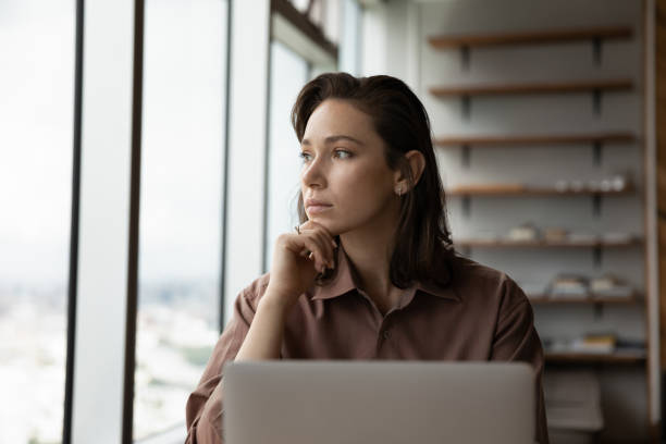 istock Pensive woman work on laptop look in distance thinking 1318858257