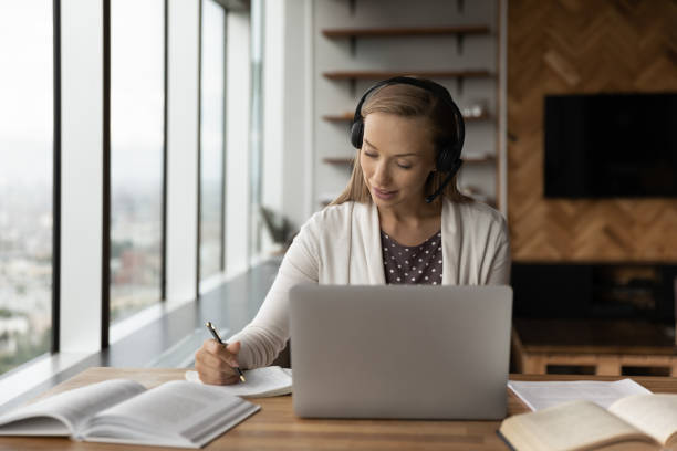 istock Young female in earphones have distant study course on laptop 1318858277