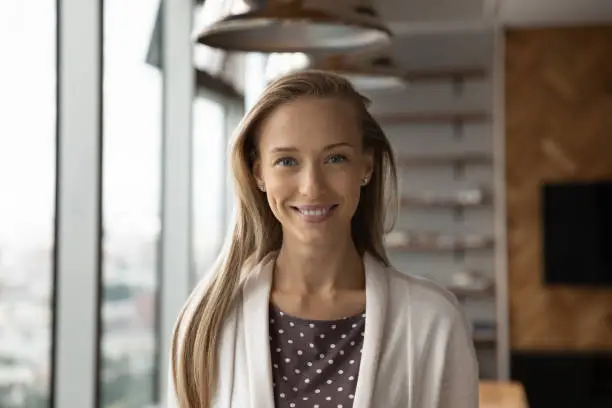 Headshot portrait of smiling young Caucasian woman employee or worker pose in modern office. Profile close up picture of happy successful confident businesswoman show leadership. Employment concept.